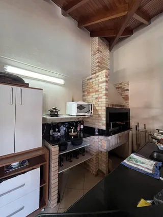 Vista interna de uma cozinha com detalhes em tijolo aparente e vigas de madeira.
