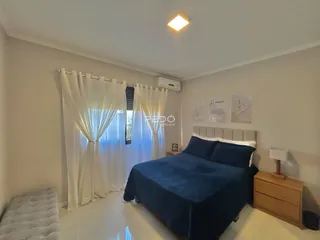 Quarto com cama azul e cortinas brancas na sala.