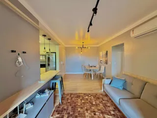 Sala de estar com sofá e mesa de jantar em um ambiente claro com piso de madeira.