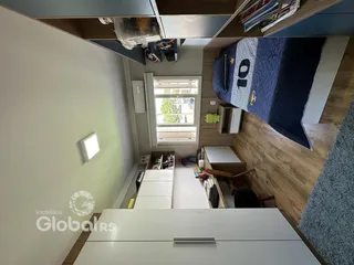 Quarto com piso de madeira e janela no interior de uma residência.