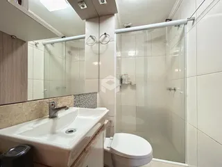 Foto de um banheiro com box de vidro e pia.