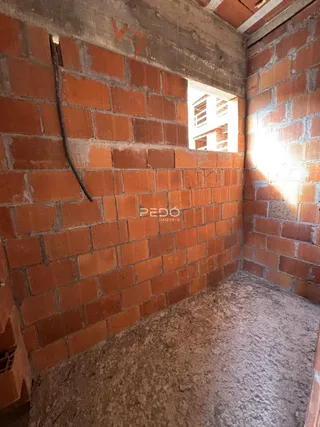 Parede interna de tijolos vermelhos expostos em uma estrutura de construção.