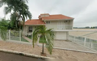 Exterior da casa residencial em Lajeado, Brasil, com muro branco e paisagismo.