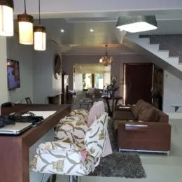 Sala de estar com móveis de madeira escura e iluminação clara.