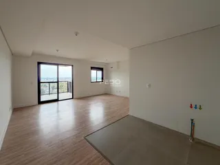 Sala de estar ampla com piso de madeira clara e grande janela.