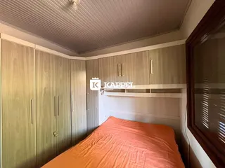 Quarto com cama e armários em madeira clara.