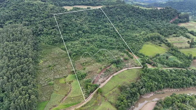 Vista aérea de uma propriedade rural com vegetação densa e áreas de campo.