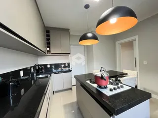Cozinha moderna com armários brancos e bancadas escuras.