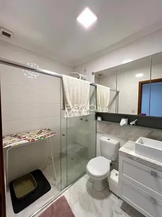 Foto de um banheiro com box de vidro e revestimento branco.