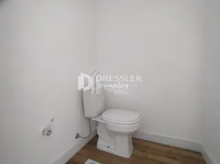 O interior de um banheiro mostra um vaso sanitário branco.