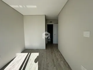 Hall de entrada com piso de madeira e paredes brancas.
