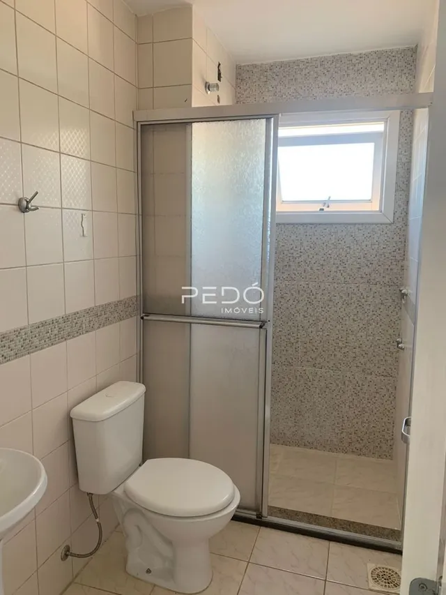 Foto de um banheiro com revestimento cerâmico e porta de vidro.