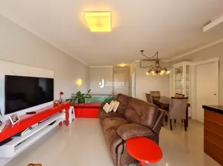 Sala de estar com sofá marrom e televisão instalada na parede.