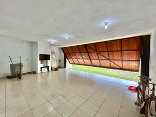 Vista de um corredor amplo com piso de cerâmica e parede de madeira em uma residência.