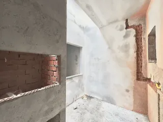 Vista interna de uma estrutura com paredes de alvenaria exposta.