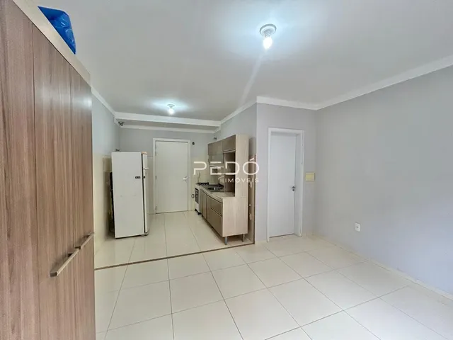 Sala de estar com piso de cerâmica e armários de madeira clara.