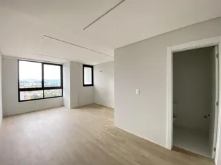 Sala de estar ampla com piso de madeira e grande janela.