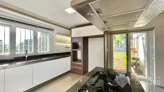 Vista da cozinha moderna com armários brancos e portas de vidro.