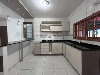 Foto da cozinha com revestimento branco e armários claros.
