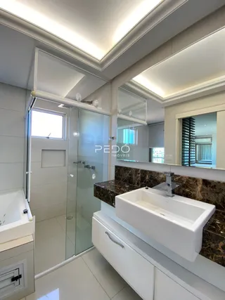 Foto de um banheiro com box de vidro e bancada de mármore.