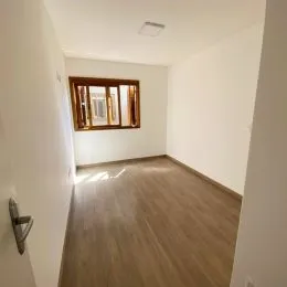 Hall de entrada com piso de madeira clara e parede branca.