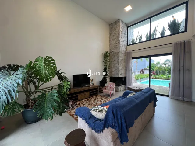 Sala de estar com vista para o jardim e piscina através de grandes janelas.