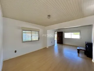 Uma sala de estar ampla com piso de madeira clara e paredes brancas.