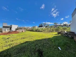 Vista aérea de um terreno com gramado e construções ao fundo.