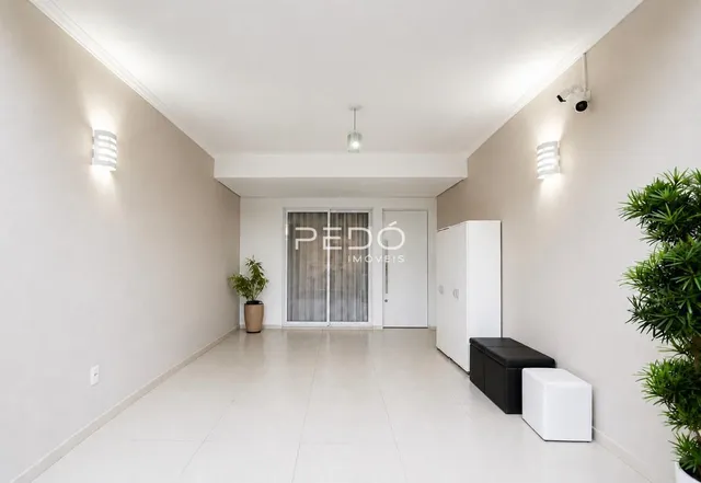 Hall de entrada com paredes brancas e piso claro.