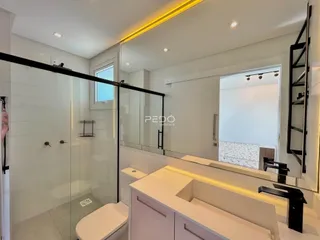 Banheiro moderno com box de vidro e bancada de apoio.