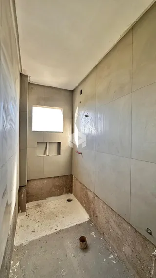 Corredor interno com paredes e piso em concreto aparente.