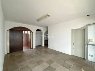 Interior de um corredor com piso de cerâmica e paredes brancas.