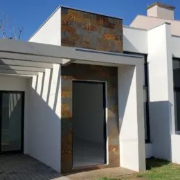Fachada externa de uma residência em Lajeado, Brasil, com revestimento em tons terrosos.