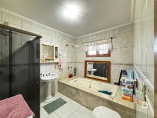Foto de um banheiro com box de vidro e banheira em cerâmica.