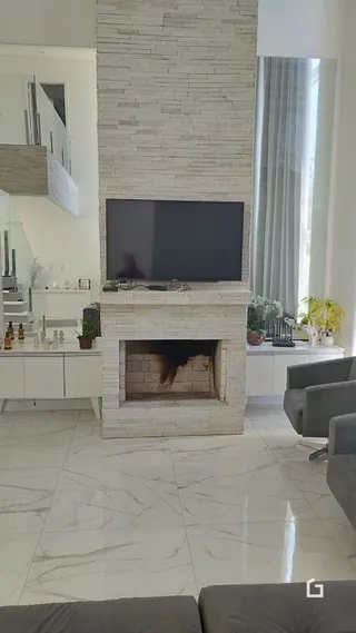 Uma sala de estar com lareira e piso de mármore claro.