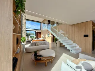 Sala de estar moderna com piso claro e escadaria de vidro em um apartamento.