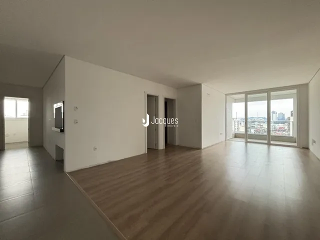 Sala de estar ampla com piso de madeira clara e portas de vidro.