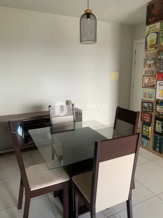 Uma sala de jantar com mesa de vidro e cadeiras de madeira.