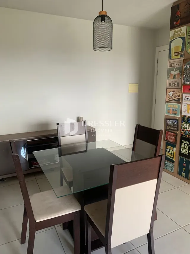Uma sala de jantar com mesa de vidro e cadeiras de madeira.