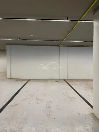 Foto de um espaço interno vazio com piso de concreto e paredes brancas.