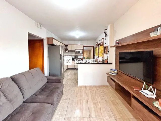 Sala de estar com sofá cinza e área de cozinha moderna.