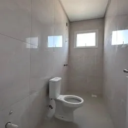 Foto interna de um banheiro com vaso sanitário branco.