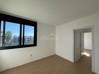 Sala de estar com piso de madeira e grande janela mostrando a vista externa.
