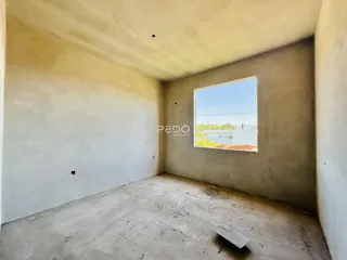 Foto de um cômodo interno com paredes e piso em estado de obra.