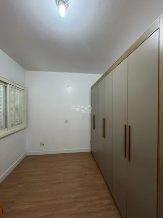 Vista interna de um cômodo com piso de madeira e armários embutidos.