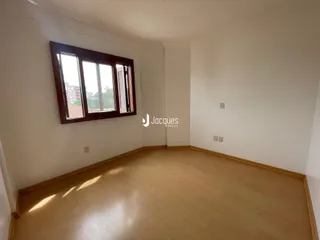Sala de estar com piso de madeira clara e janela.