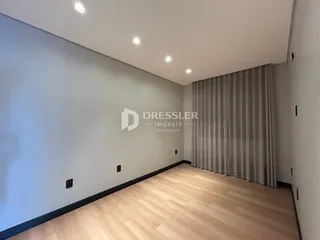 Ambiente interno com piso de madeira clara e paredes cinzas.