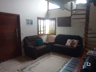 Sala de estar com dois sofás e uma escada de madeira.