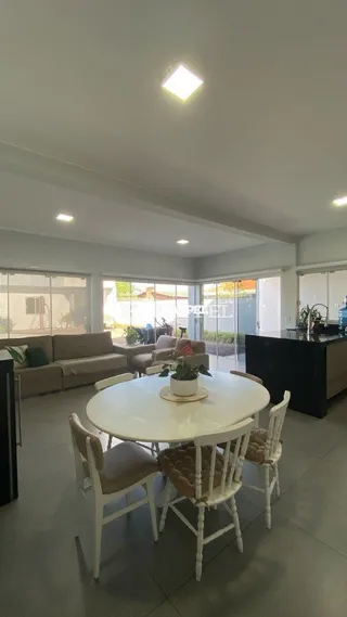 Uma sala de jantar com mesa redonda e cadeiras brancas é visível na propriedade.