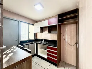 Imagem de uma cozinha com armários e revestimentos claros em Lajeado.